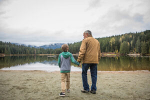 Grandfather and grandson walking at a lake.